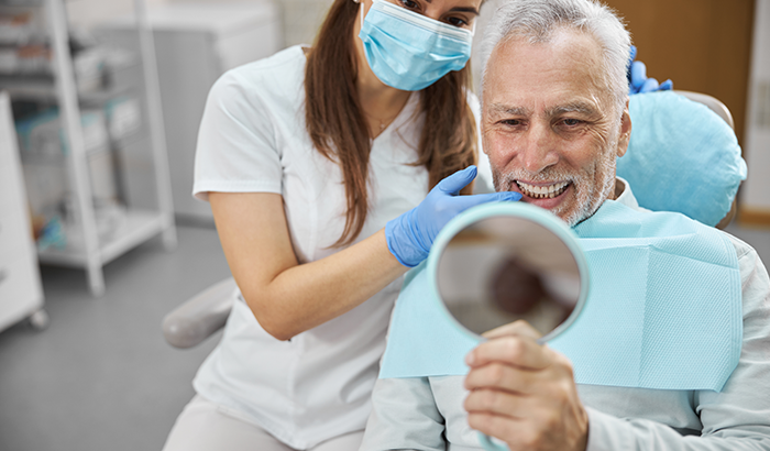 A man checking his smile after dental implant placment, at North Hills Implant & Oral Surgery in Raleigh, NC.